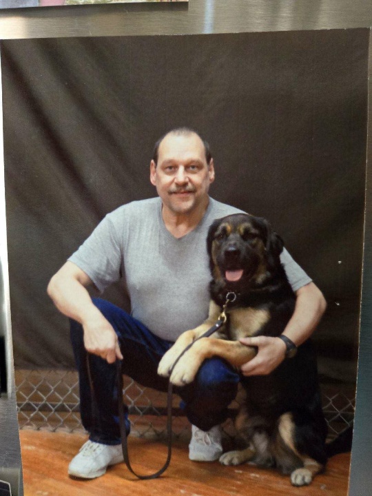 Werner Kunkel kneeling down next to a dog he helped to train while in prison